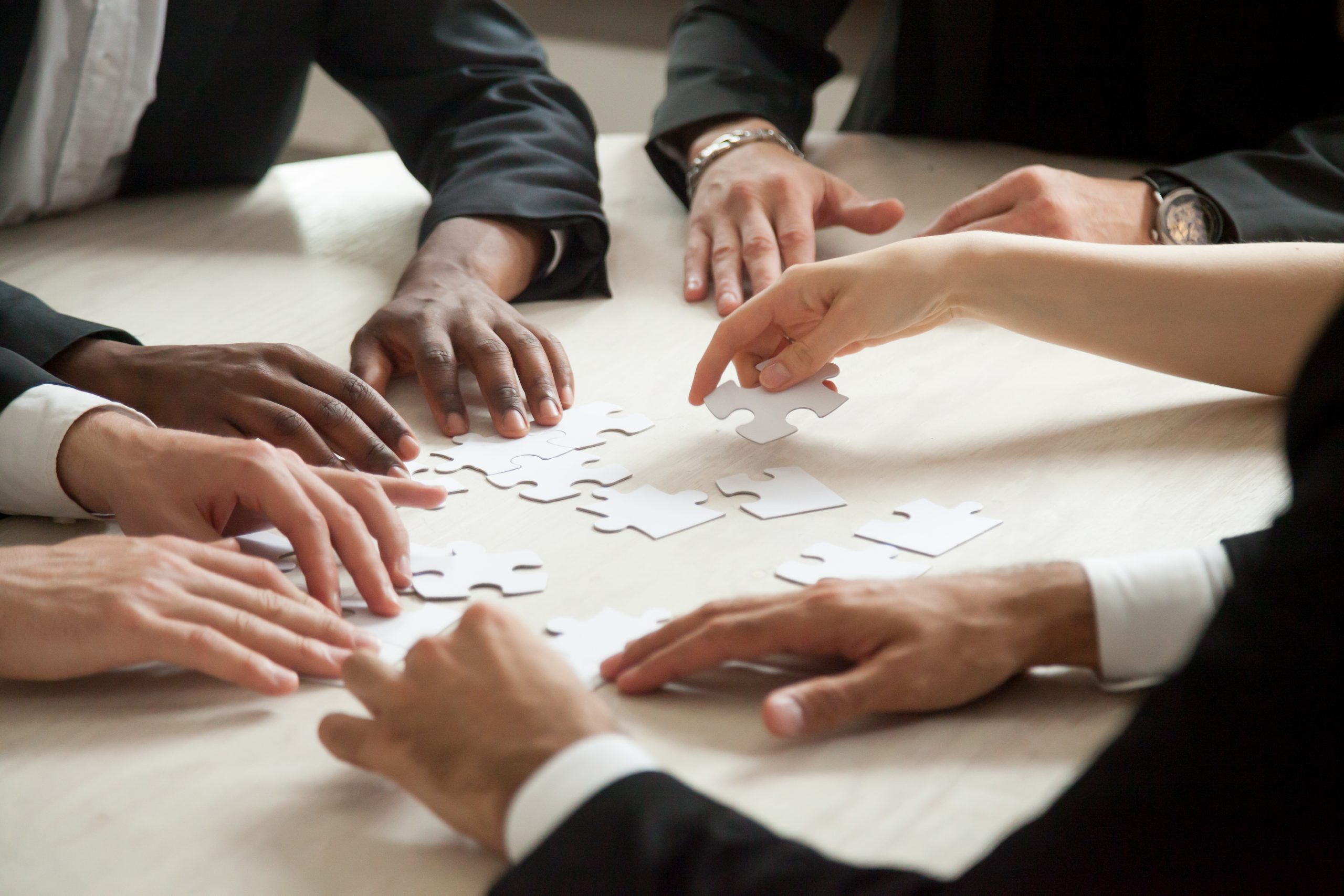 close-up-multiethnic-team-solving-blank-puzzle-game-scaled