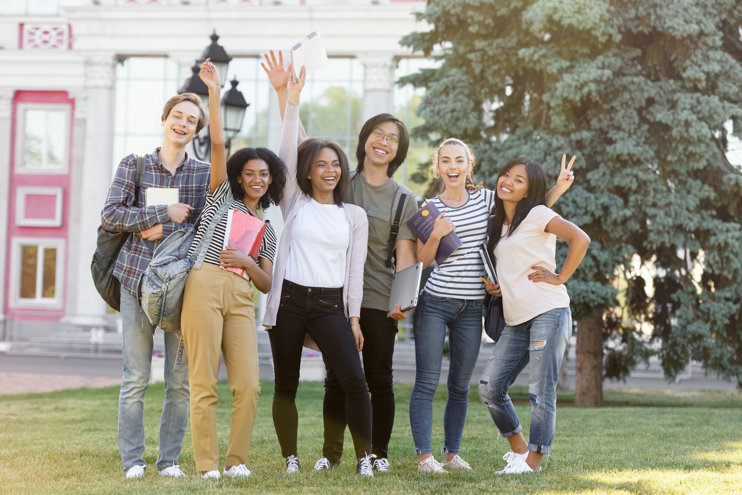 cheerful-students-standing-waving-outdoors-scaled